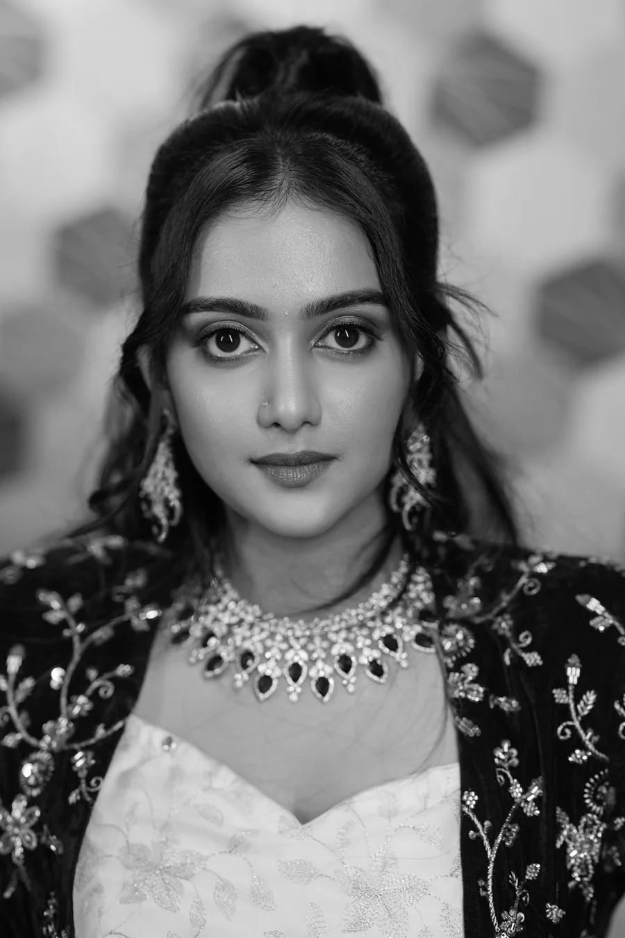 Black and white portrait of Harini Veena wearing a statement sapphire necklace