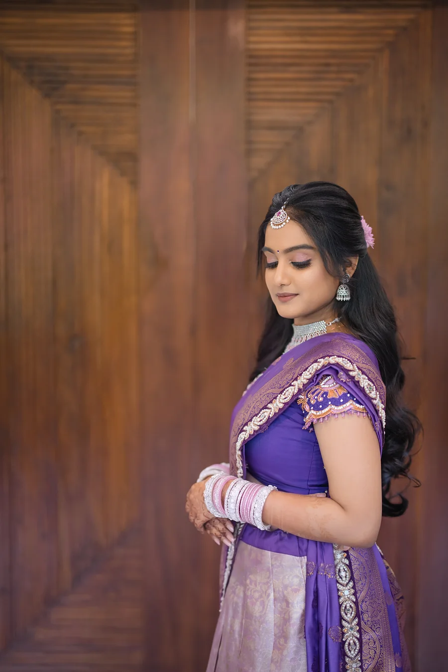 Harini Veena looking down in a lavender half-saree with pink and silver bangles