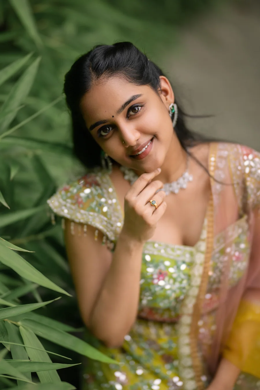 Harini Veena smiling among leaves in an embellished lime lehenga