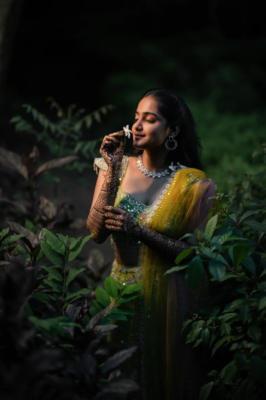 Harini Veena in a lime lehenga with mehendi, holding a flower in soft evening light