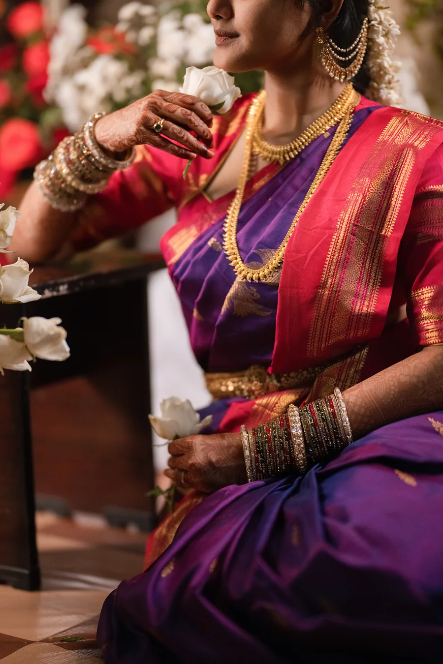 Close-up of layered temple gold necklaces and bangles on a magenta silk saree